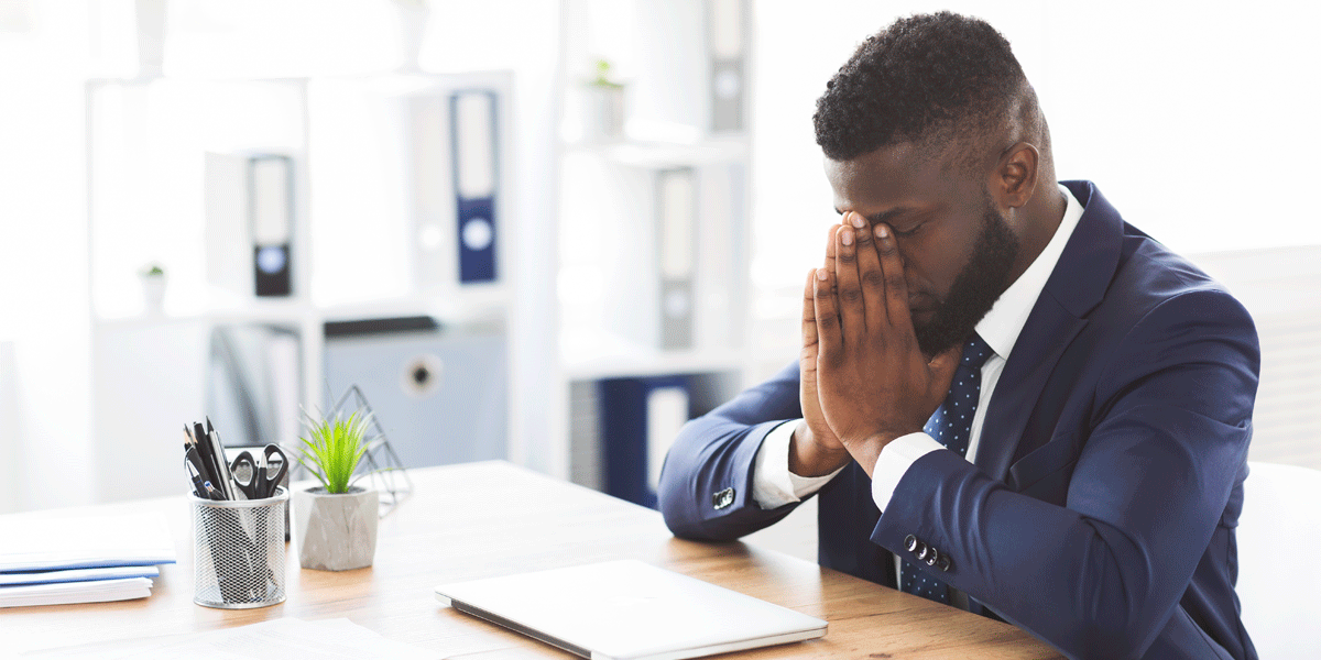 Stressed man at work with his head in his hands.